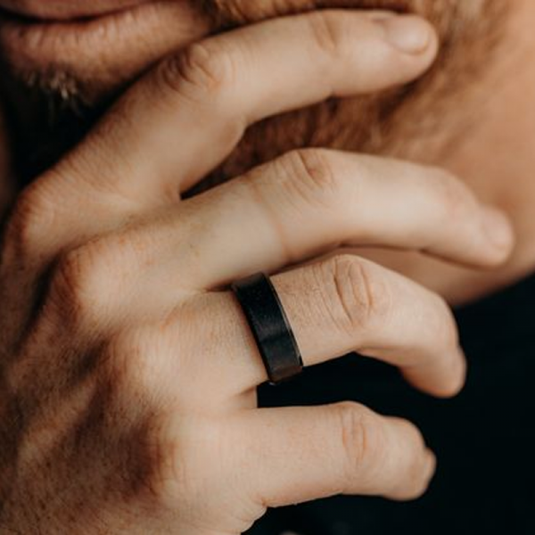 A man's hand wearing a black tungsten ring which is modern and sleek.