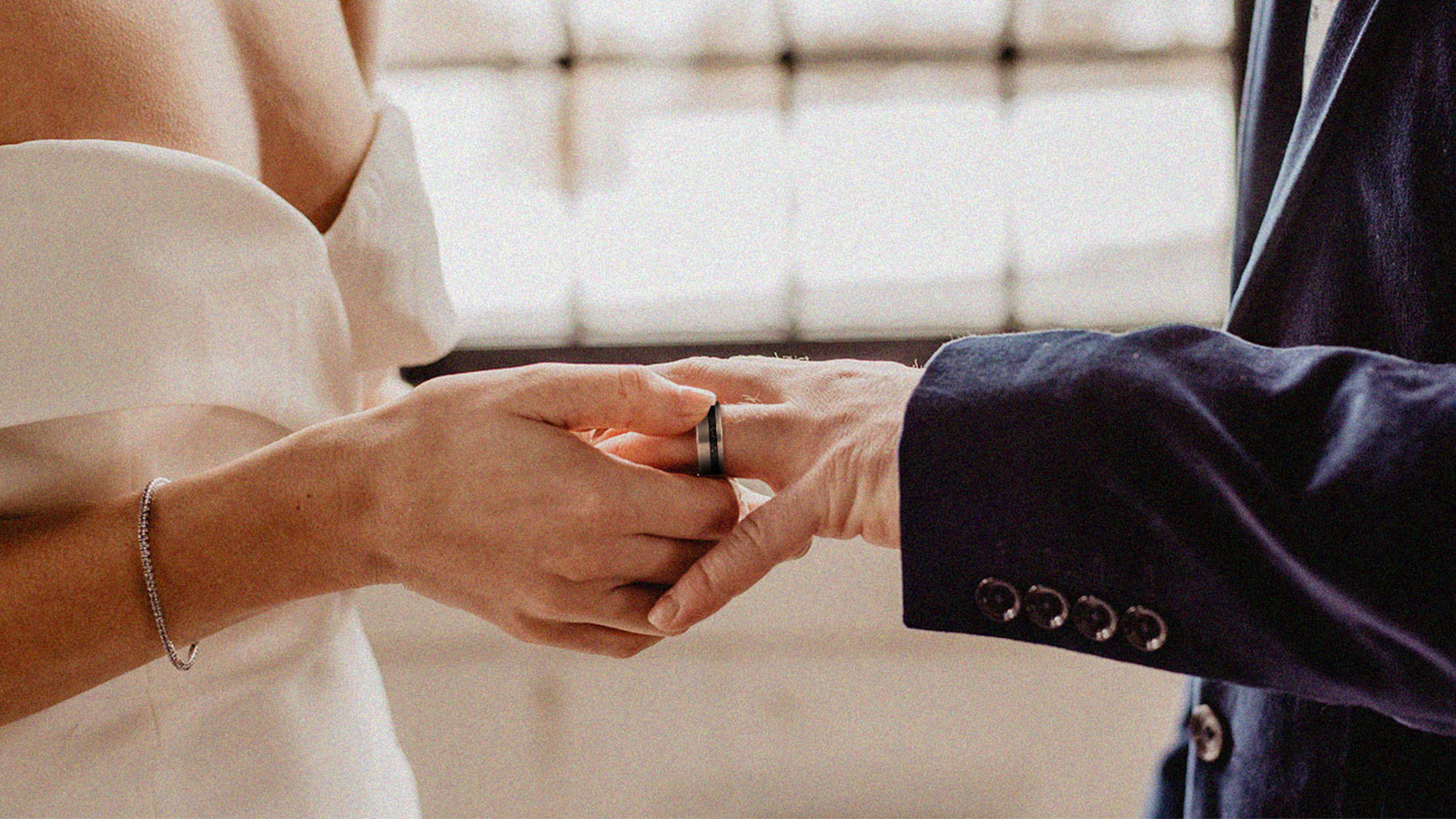 A woman puts a ring on a man's finger at a wedding