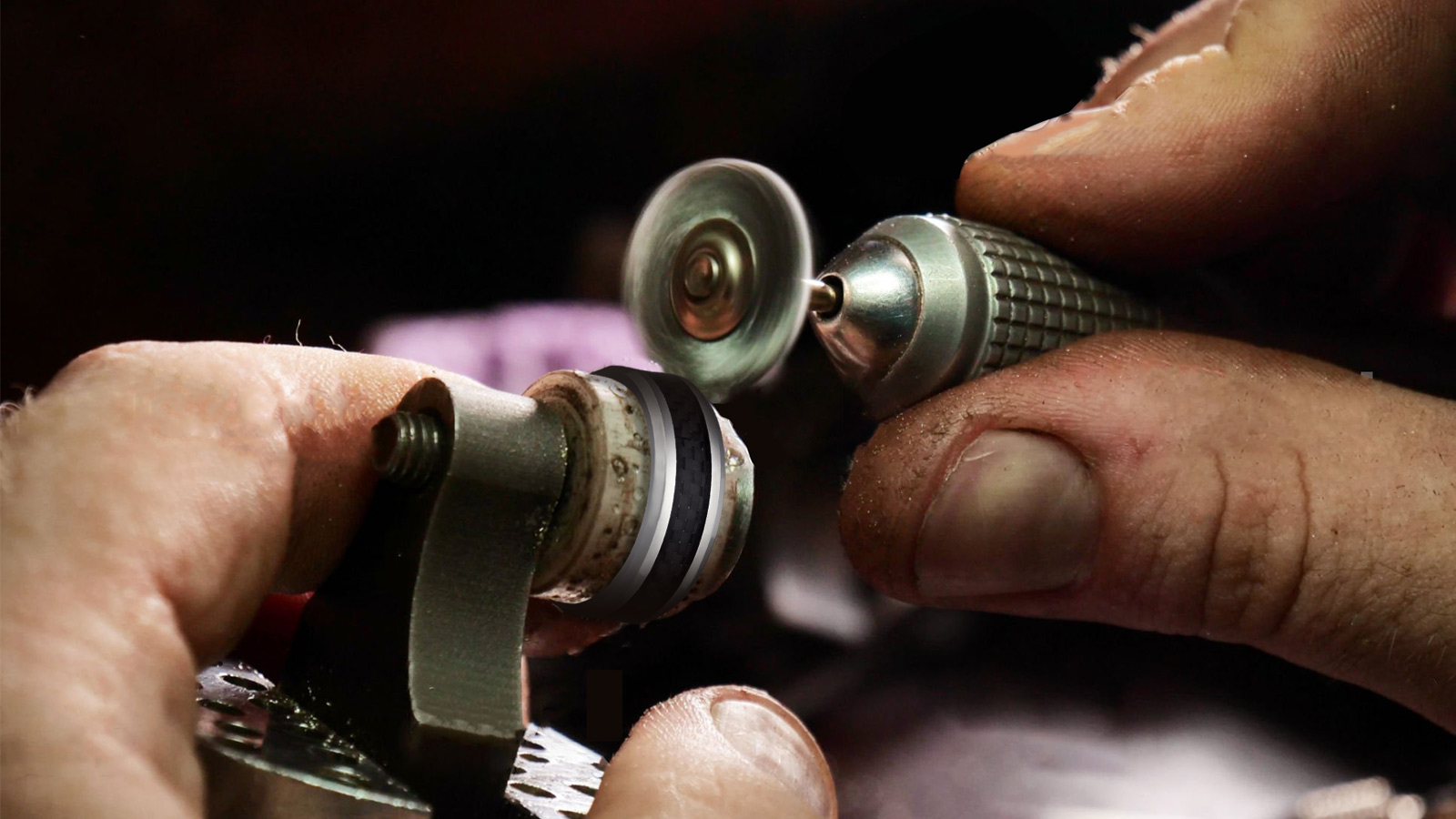 The man is using an instrument to polish the men's ring