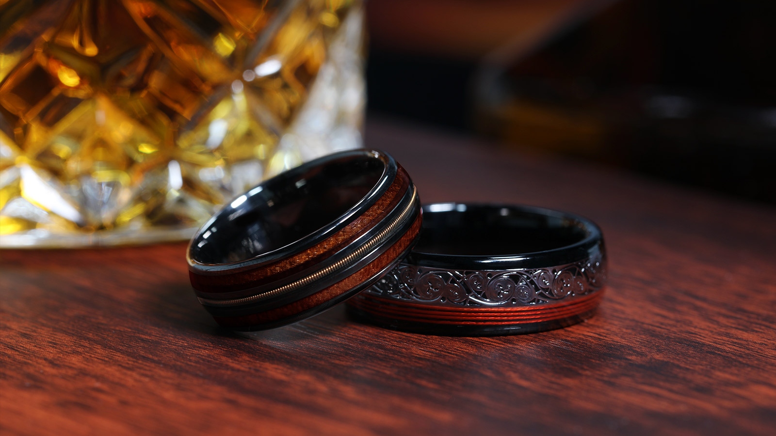 Two men's rings were placed on a wooden table with beer glasses behind them