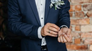 The groom in a suit with a wedding band on his hand