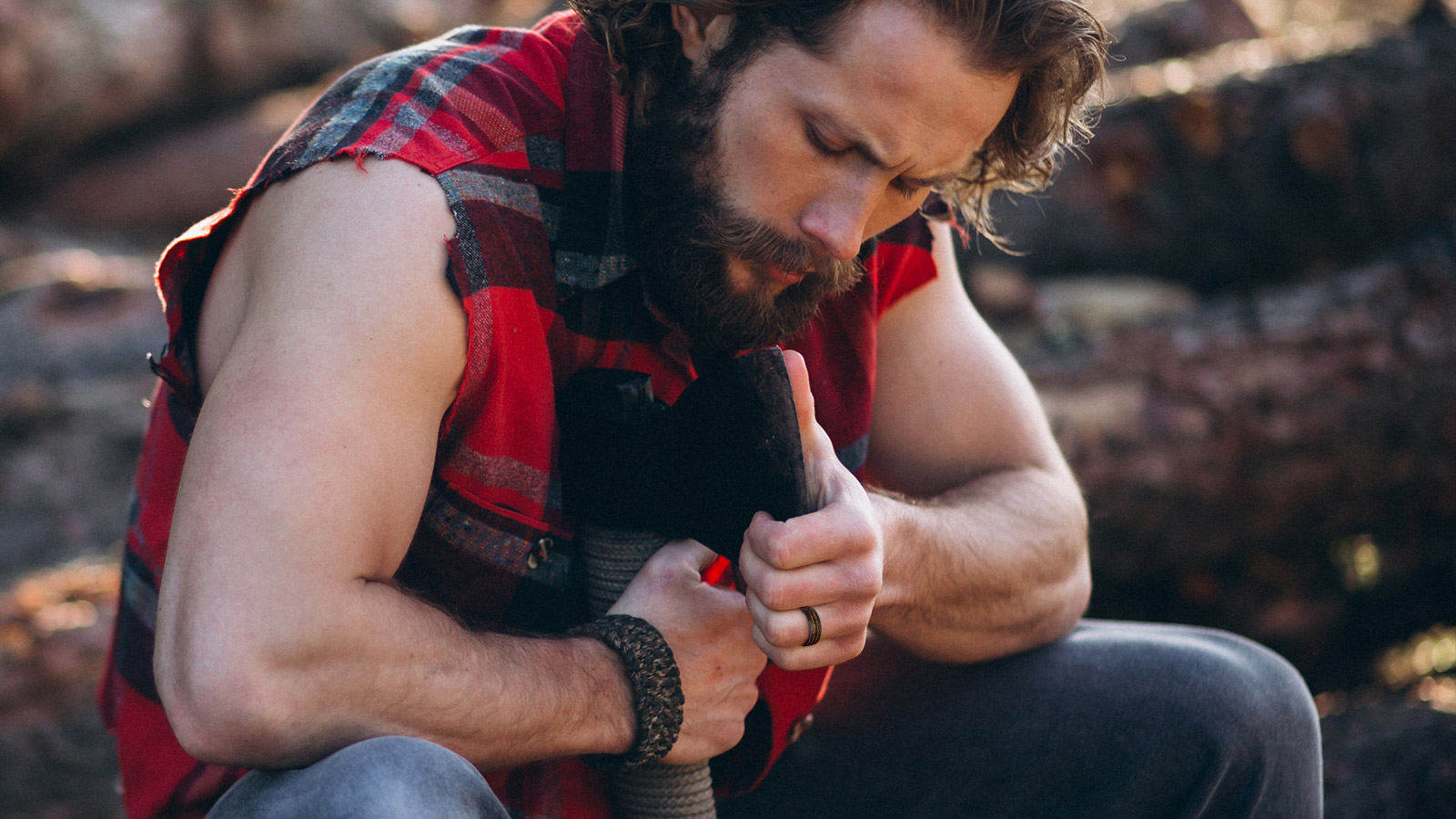 A man in a red plaid shirt with a man's ring on his finger was tightening an axe