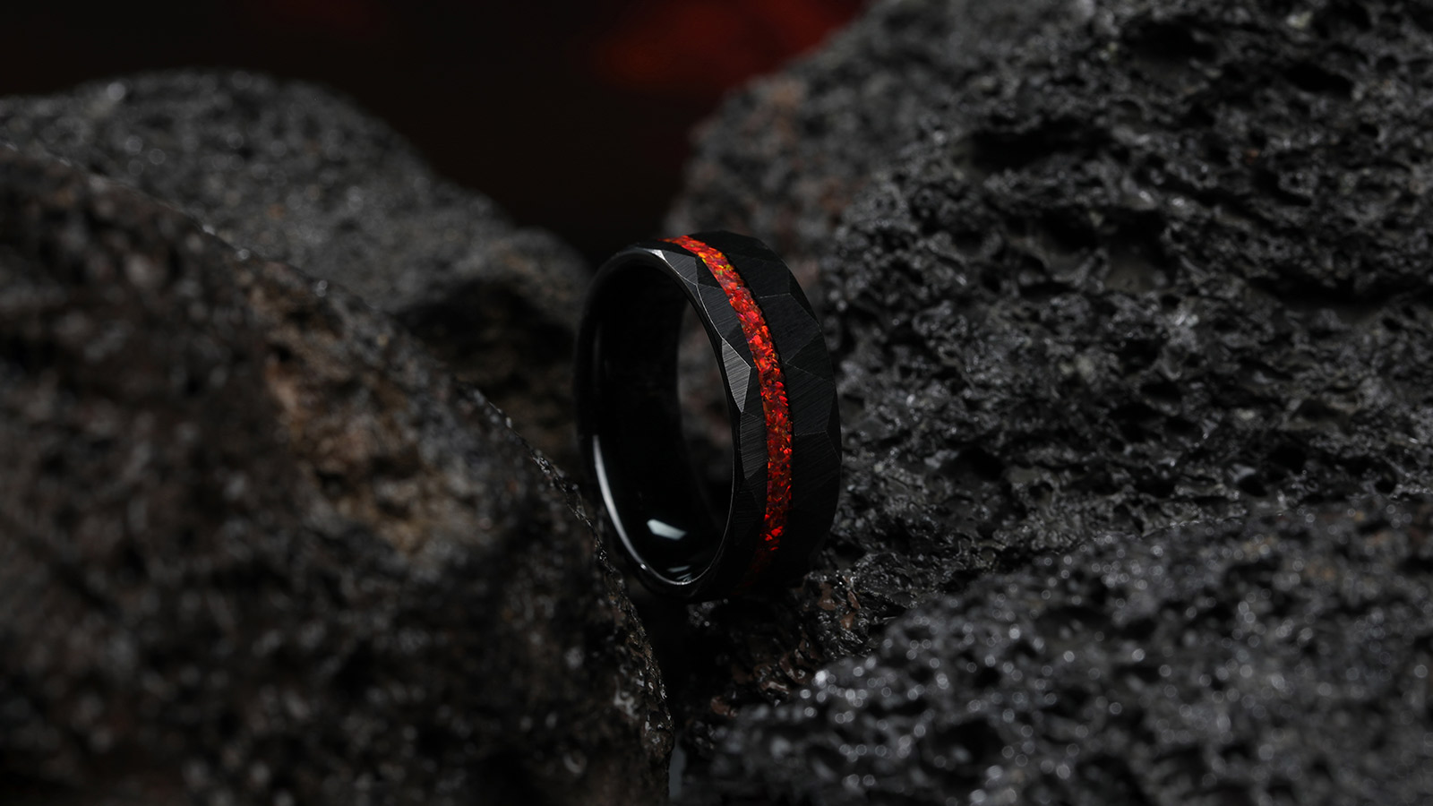 A minimalist black wedding ring with a red setting in the middle